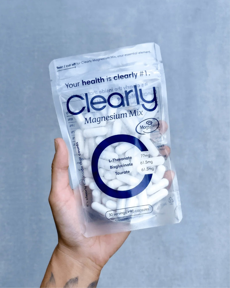 Clearly Magnesium Mix supplement in a clear container with a scoop, showing the magnesium powder inside.